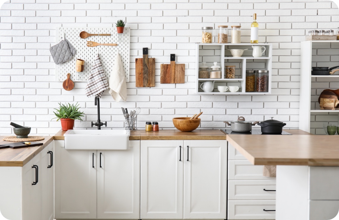 Helle Landhausküche mit weißen Schränken, Holzarbeitsplatte, offener Ablage und dekorativer Wandorganisation.