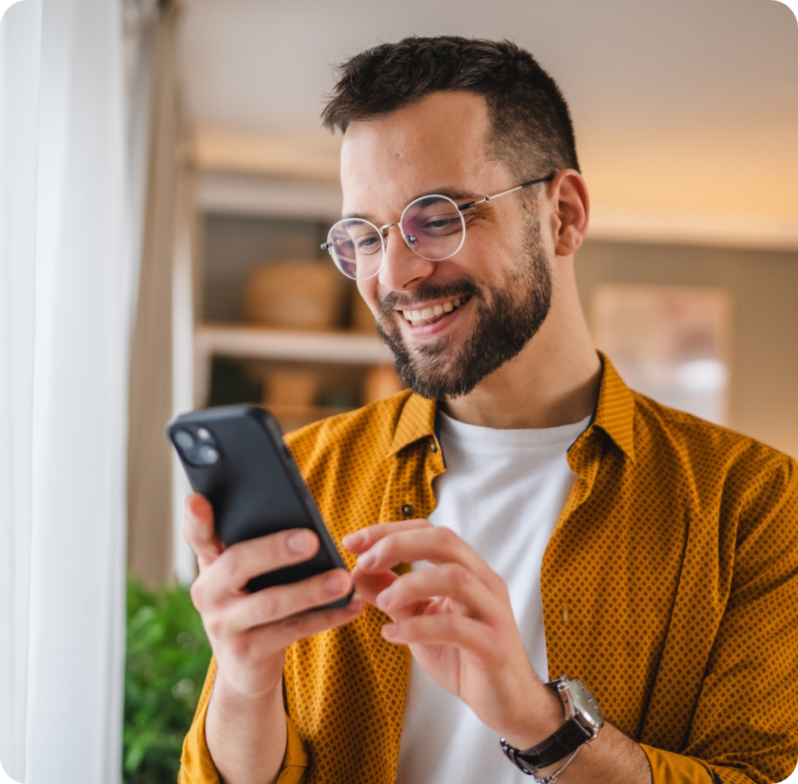 Mann schaut sich auf dem Handy etwas an und freut sich dabei.