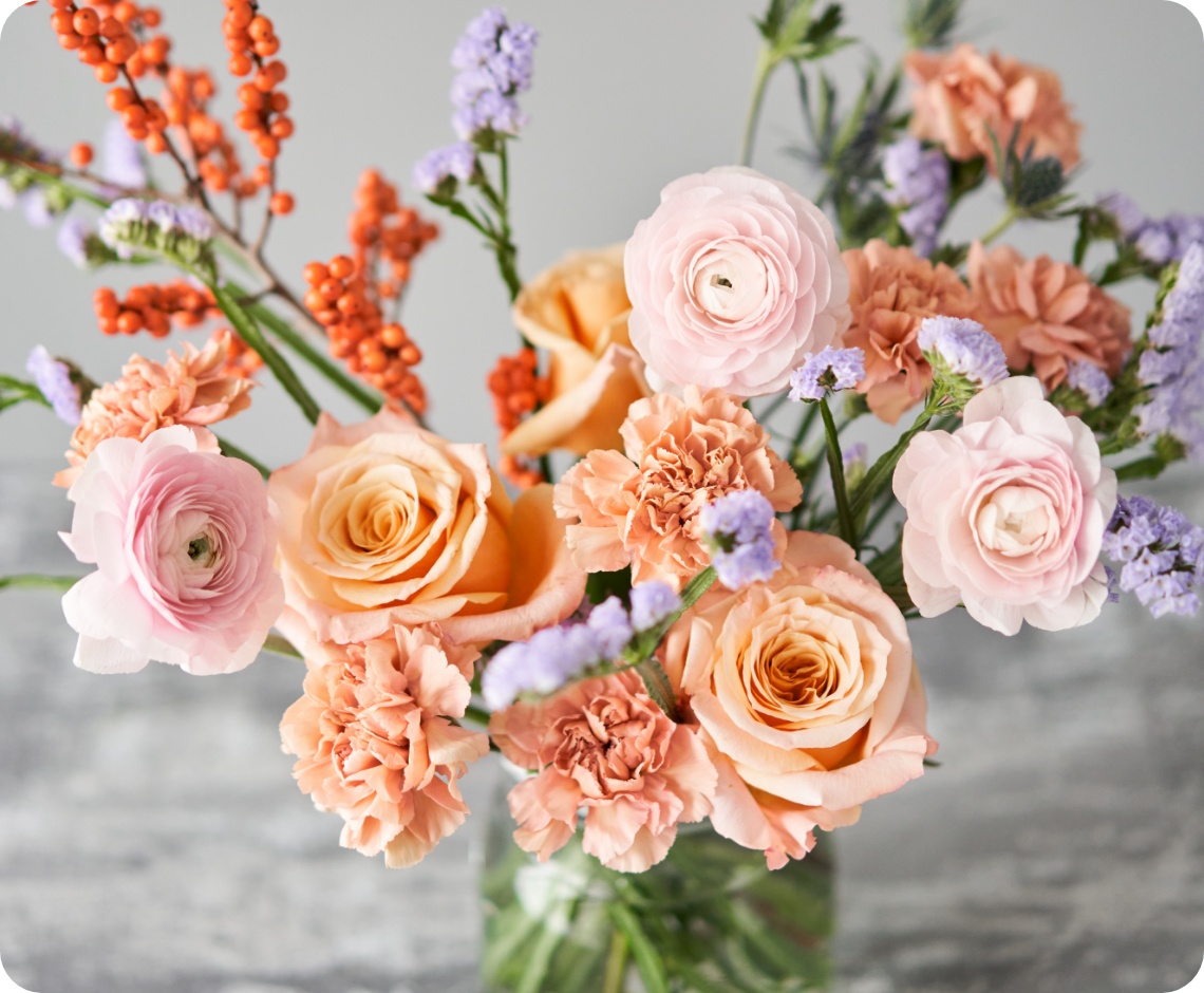 Frischer Blumenstrauß in der Vase mit rosa und aprikotfarbenen Blumen.
