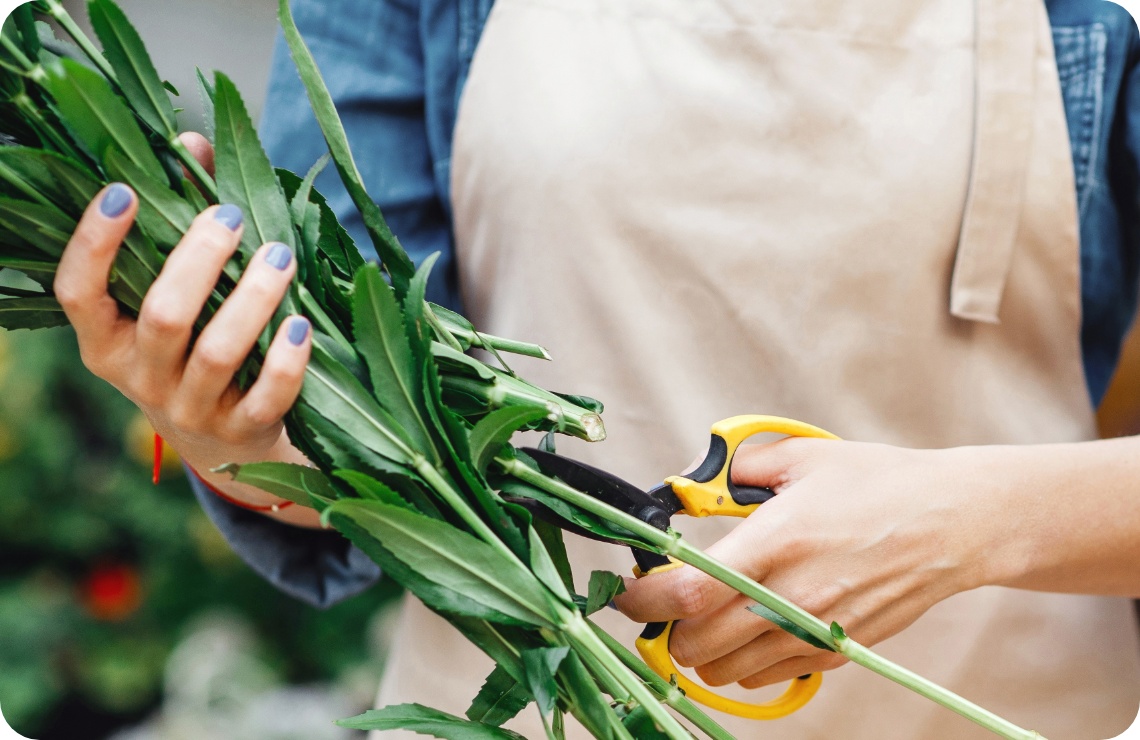 Floristin schneidet das Grün kurz für den Strauß.