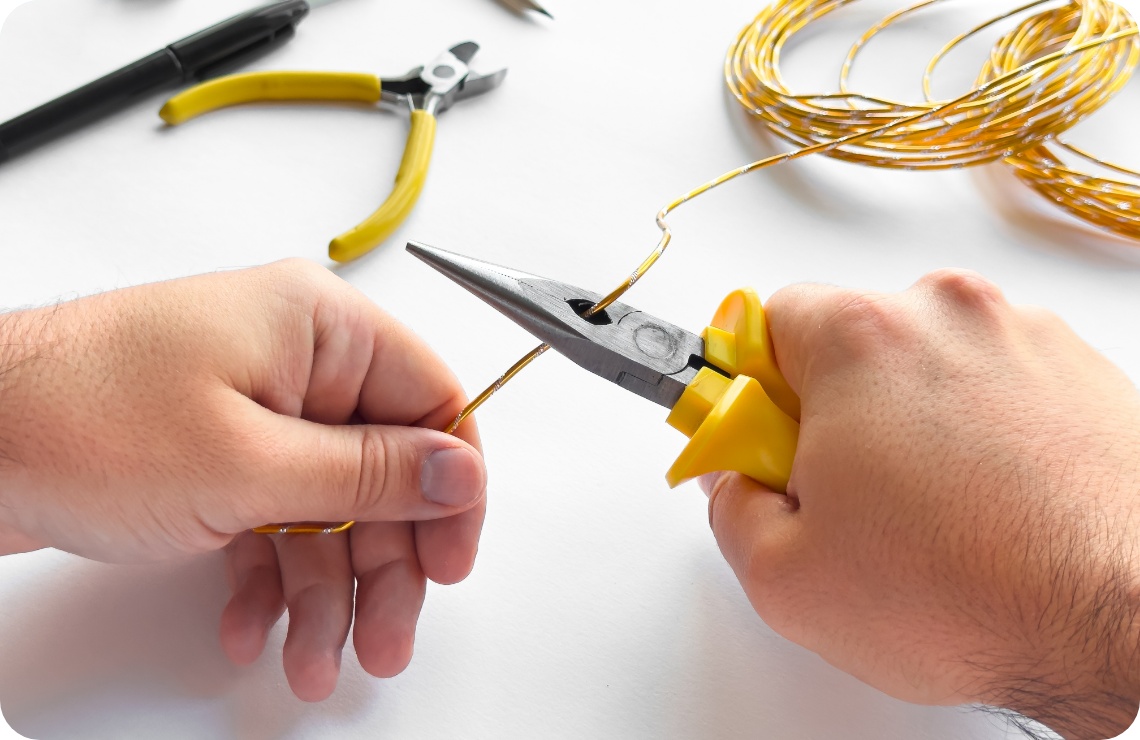 Person schneidet gelben Basteldraht.