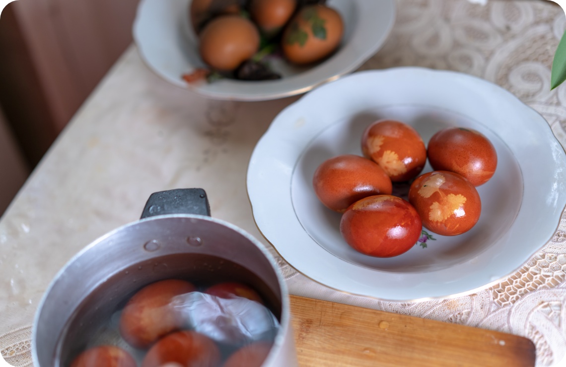 Braun-rot gefärbte Ostereier mit Blattmustern verziert auf einem Teller.