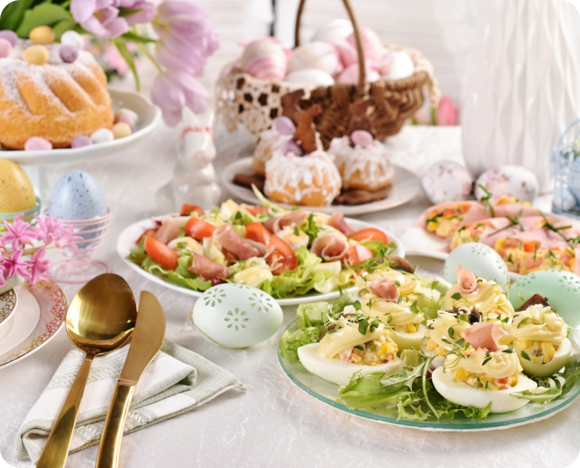 Osterbrunch mit gefüllten Eiern, Schinkensalat, Mini-Gugelhupf, Osterkuchen, bunten Eiern und Frühlingsdeko.