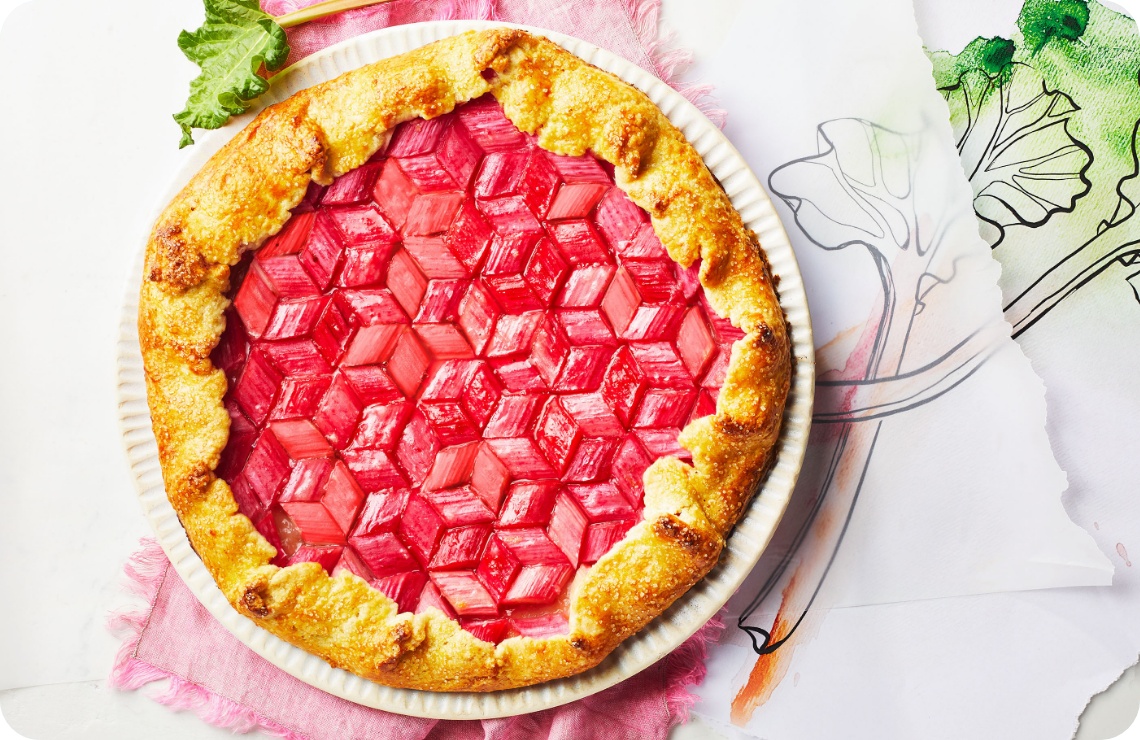Rustikale Rhabarber-Galette mit geometrischem Muster aus roten Rhabarberstücken auf goldbraunem Teig, serviert auf einem weißen Teller.