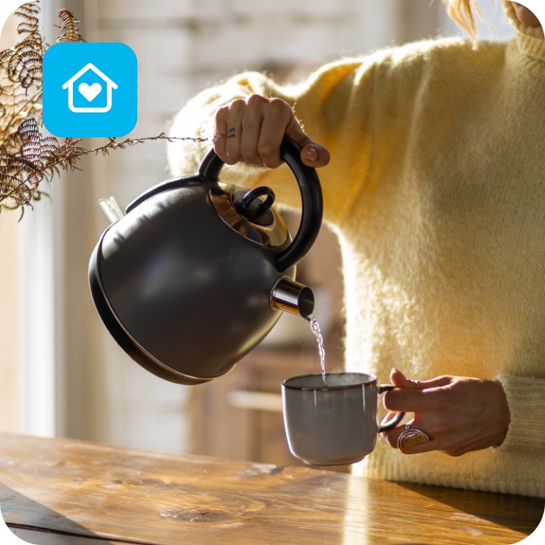 Eine Frau schenkt sich heißes Wasser in eine Tasse.