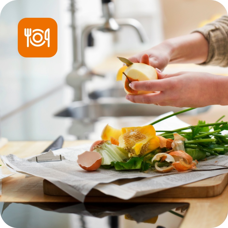 Person schält Apfel in moderner Küche, weitere Gemüsereste auf der Arbeitsplatte.