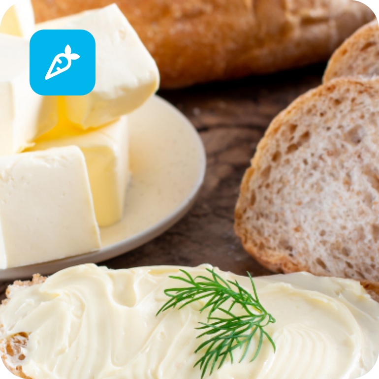 Frisches Bauernbrot mit Butter und Dill, daneben Butterwürfel auf Teller.