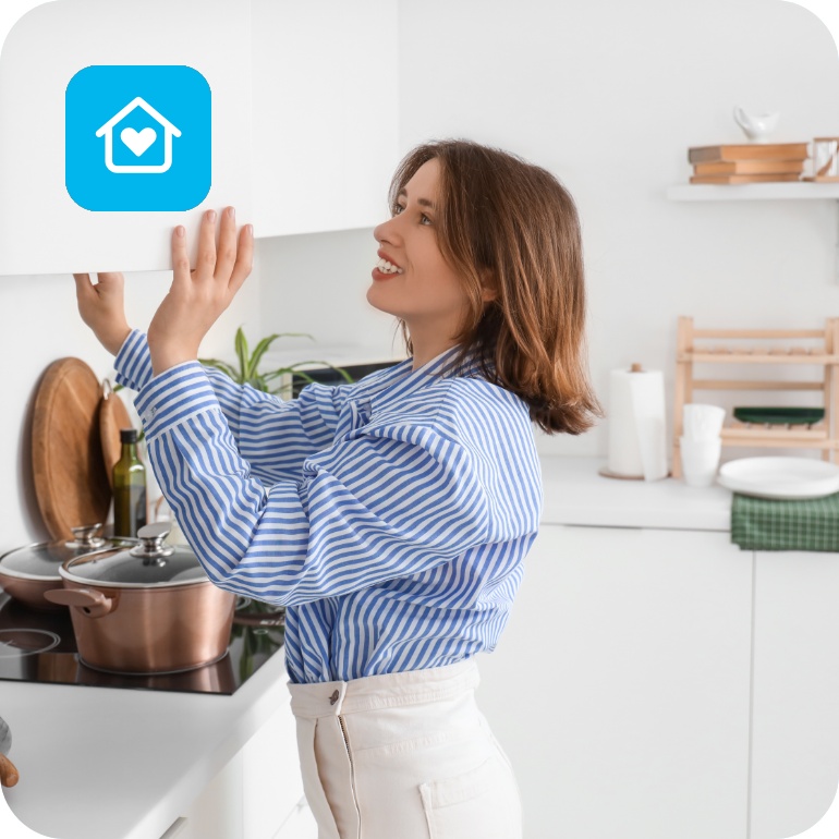 Frau in blau-weiß gestreifter Bluse öffnet einen Küchenschrank in einer modernen weißen Küche.