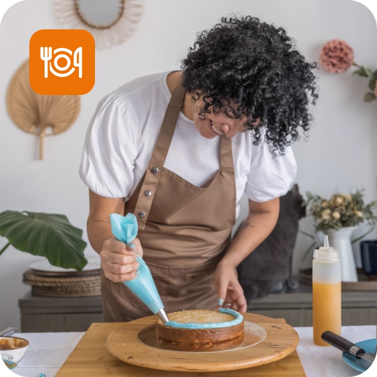 Eine Frau dekoriert mit einem Spritzbeutel einen Kuchen mit blauer Creme.