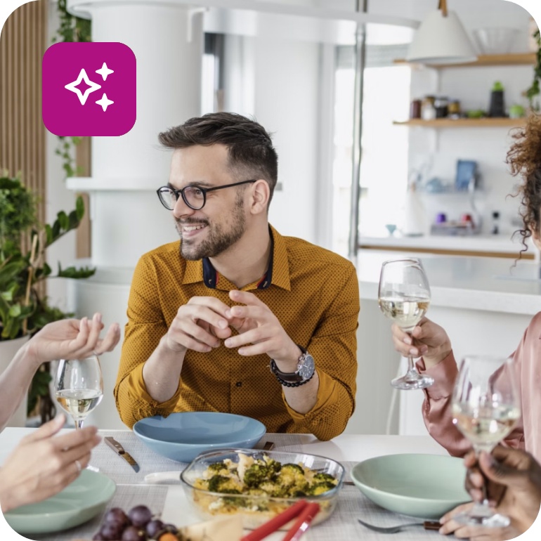 Gruppe von Gästen genießt ein gemeinsames Essen und Wein am gedeckten Tisch.