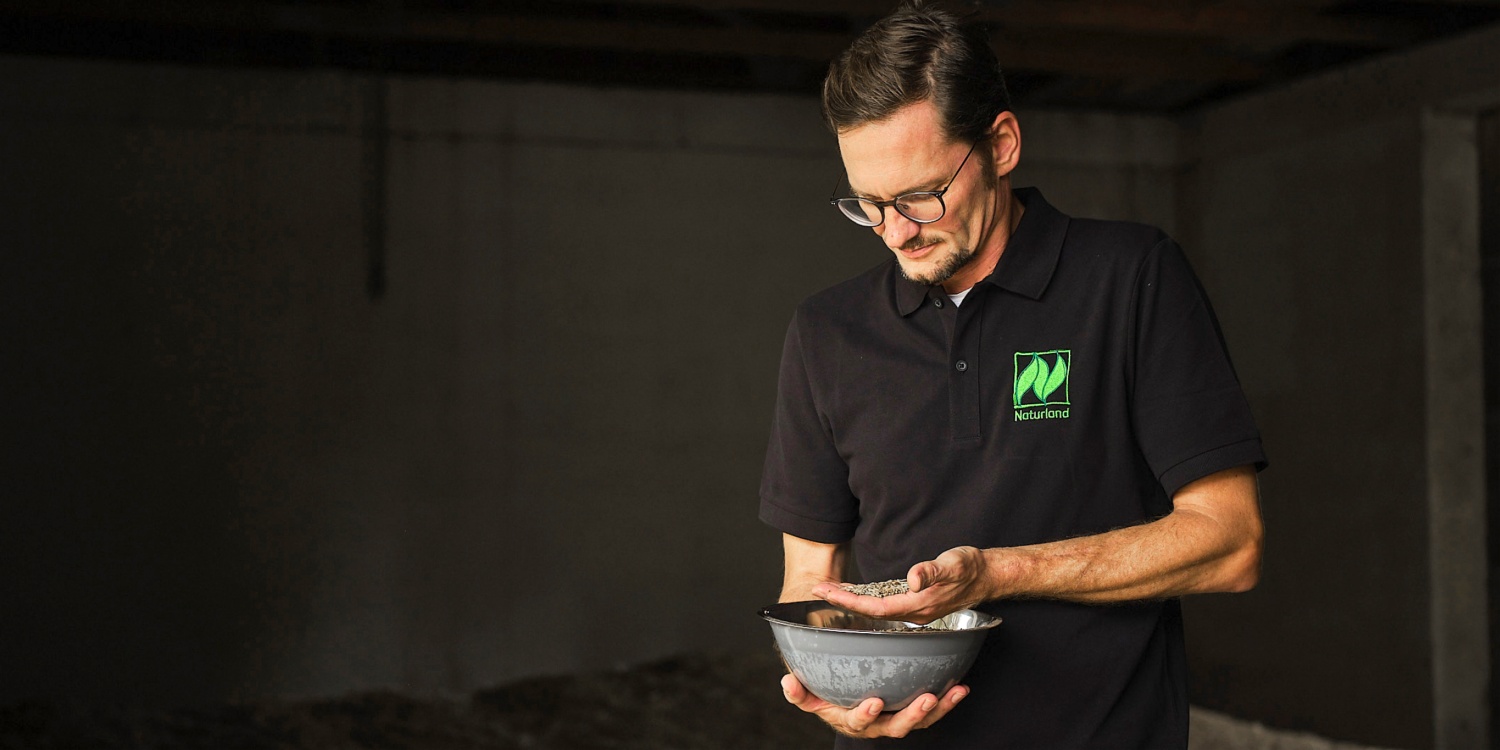 Stefan Berthold hält eine Schale Getreide in den Händen.