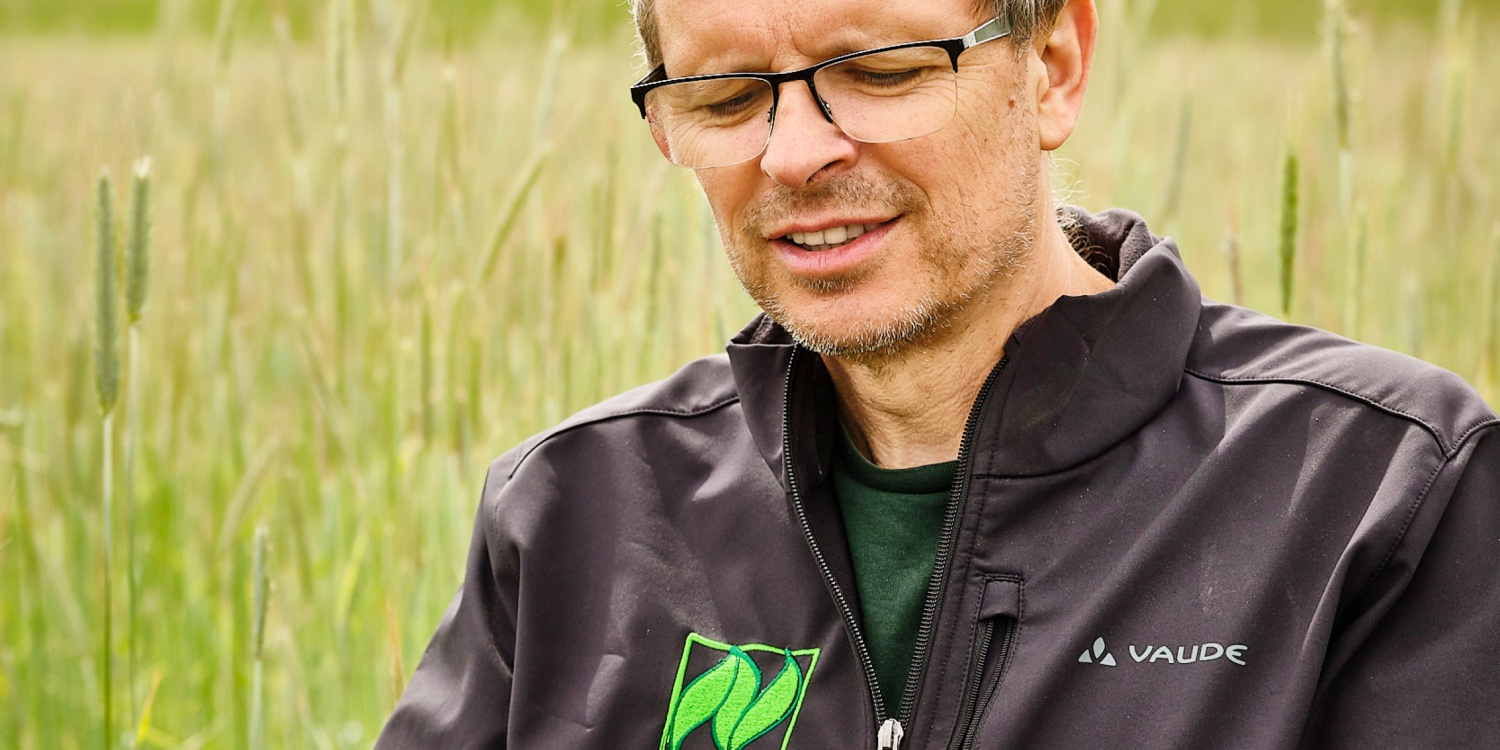 Georg Hau betrachtet eine Getreide-Ähre.