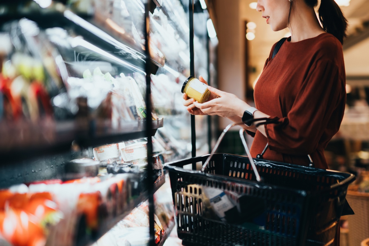 Person betrachtet ein Produkt in einem Supermarktregal.