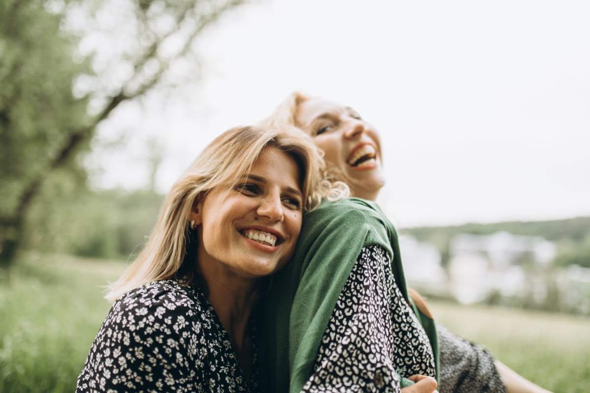 Zwei Frauen lachen zusammen im Freien und genießen die Natur.