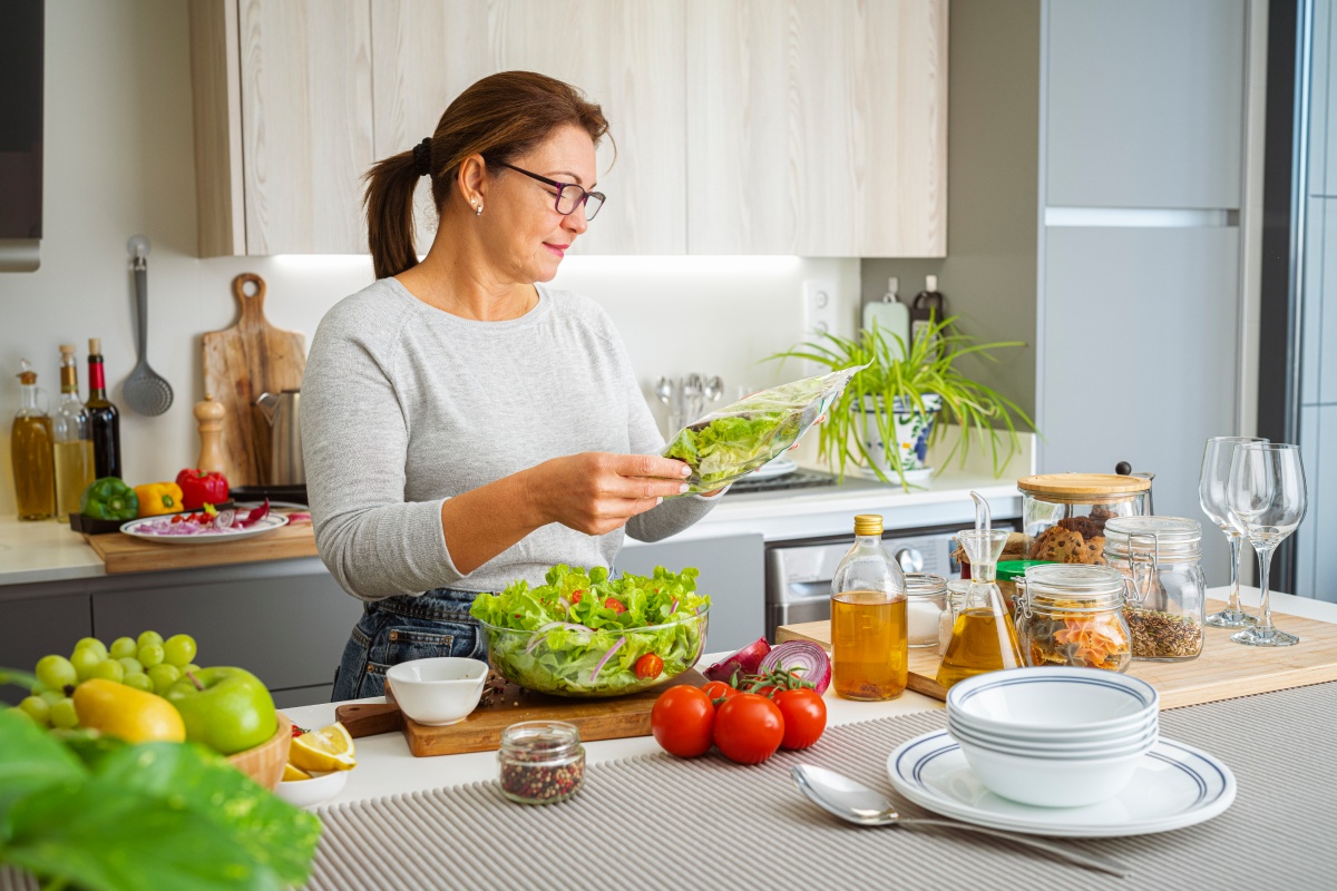 Eine Frau bereitet in der Küche einen frischen Salat mit Tomaten und Olivenöl zu.