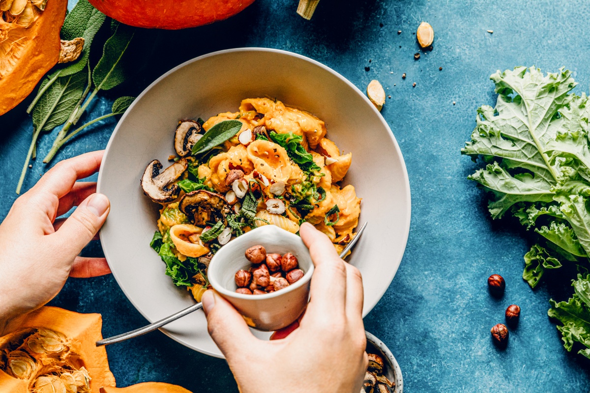 Eine Person bereitet Gemüse-Gericht in Schale zu.