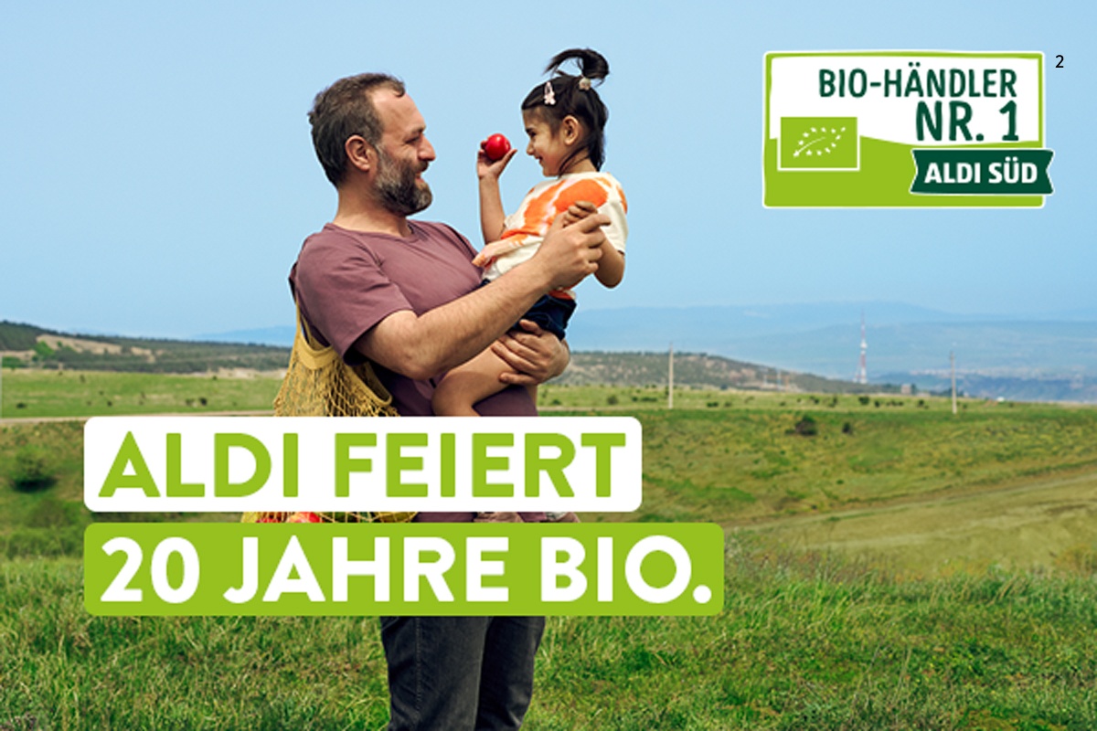 Landwirt steht auf der Weide und hält seine Tochter in den Armen.