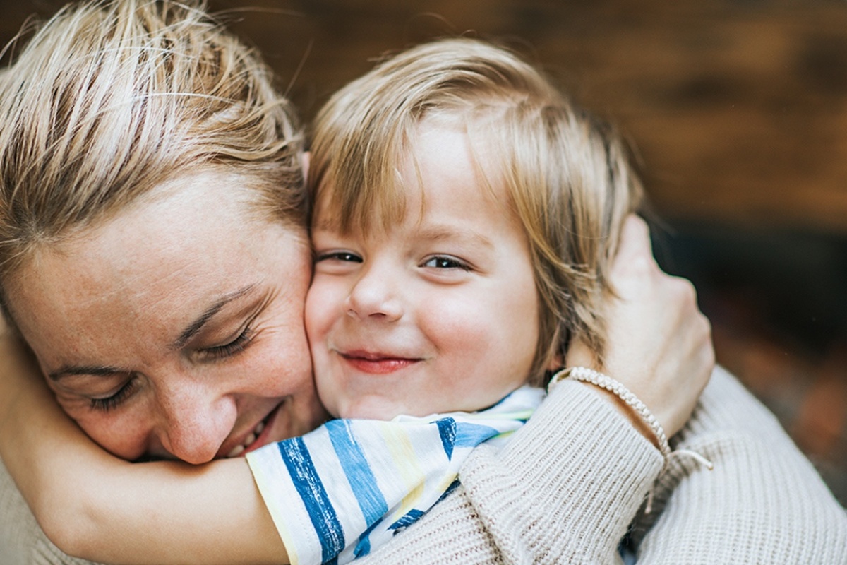 Eine Mutter hält ihr lächelndes Kind in den Armen.
