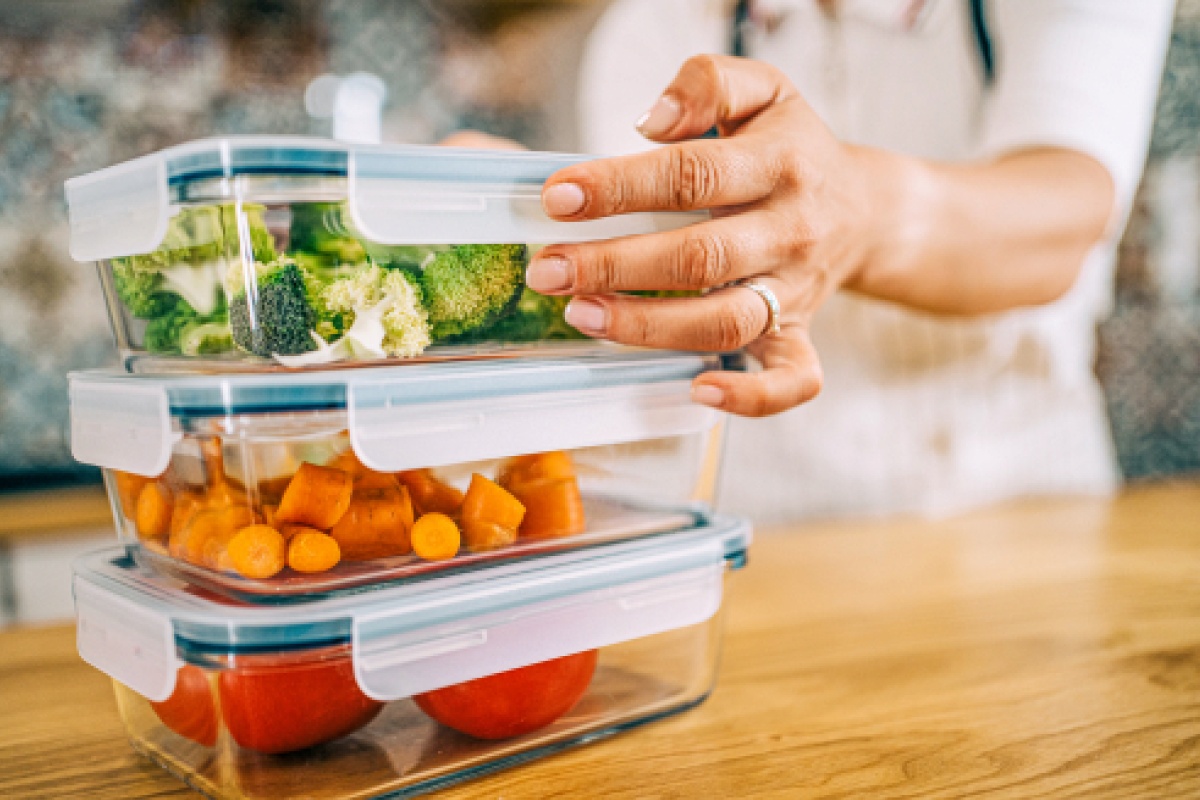 Eine Frau hat Gemüse und Reste in Tupperschüsseln zur Lagerung verpackt.