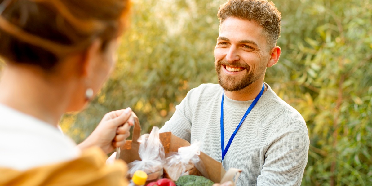 Ein Mann reicht einer Frau einer Tüte voller gespendeter Lebensmittel.