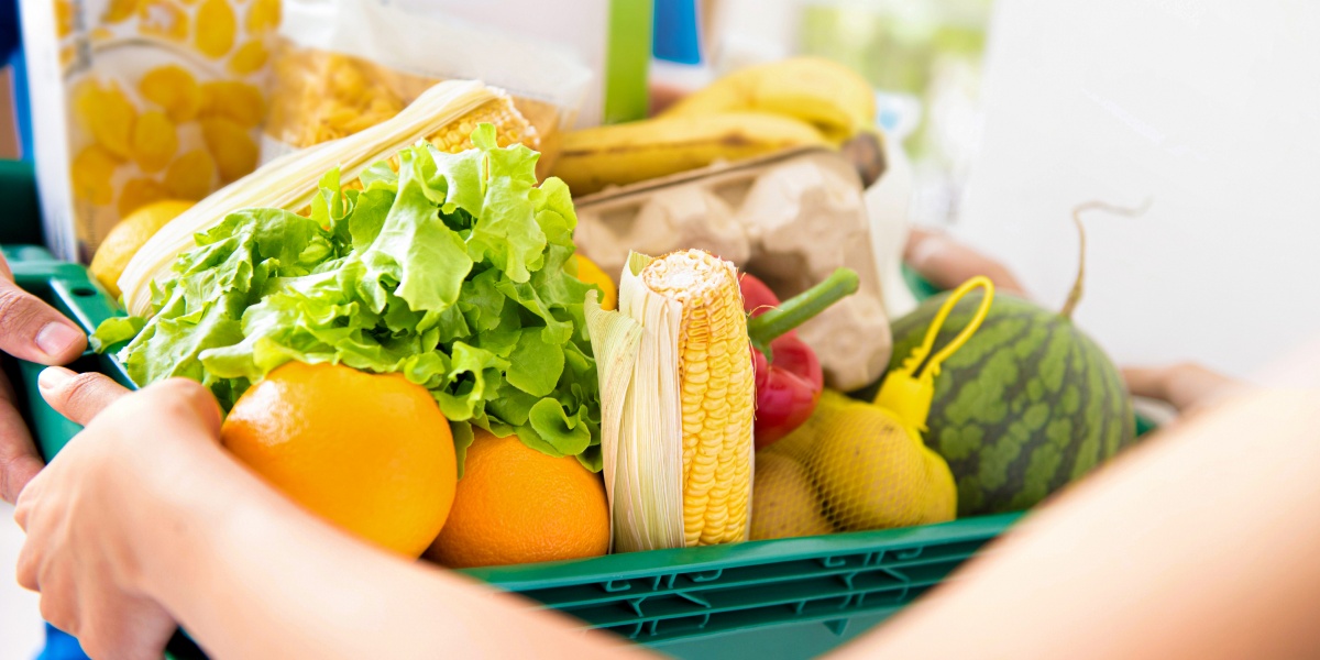 Zwei Personen greifen nach einem mit Lebensmitteln gefüllten Korb.
