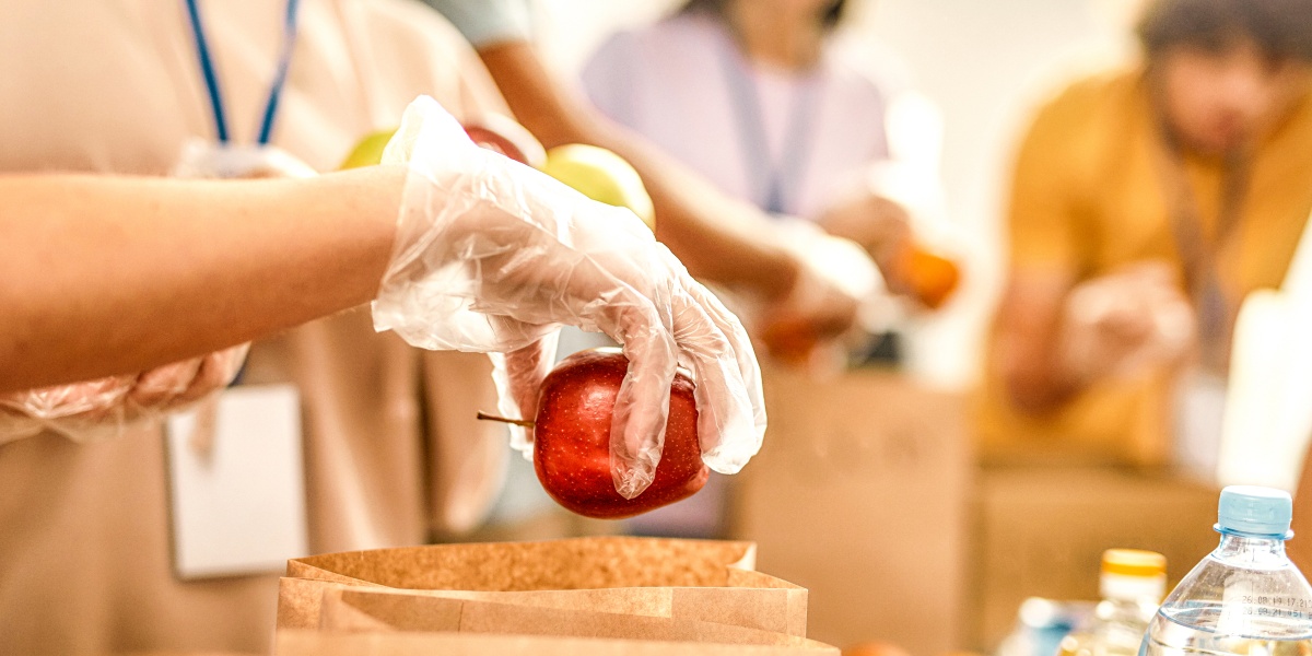 Mehrere Helfer packen Lebensmittel in Tüten.
