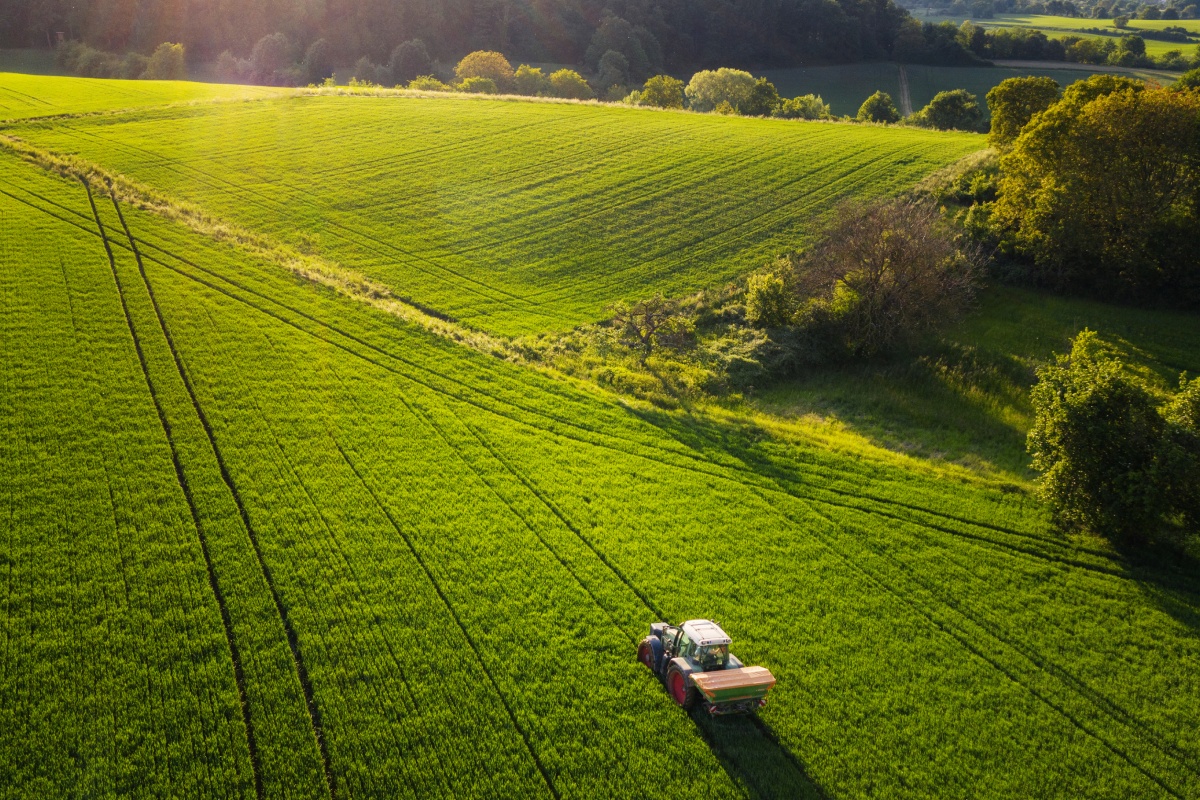 Ein Traktor fährt über ein grünes Feld.
