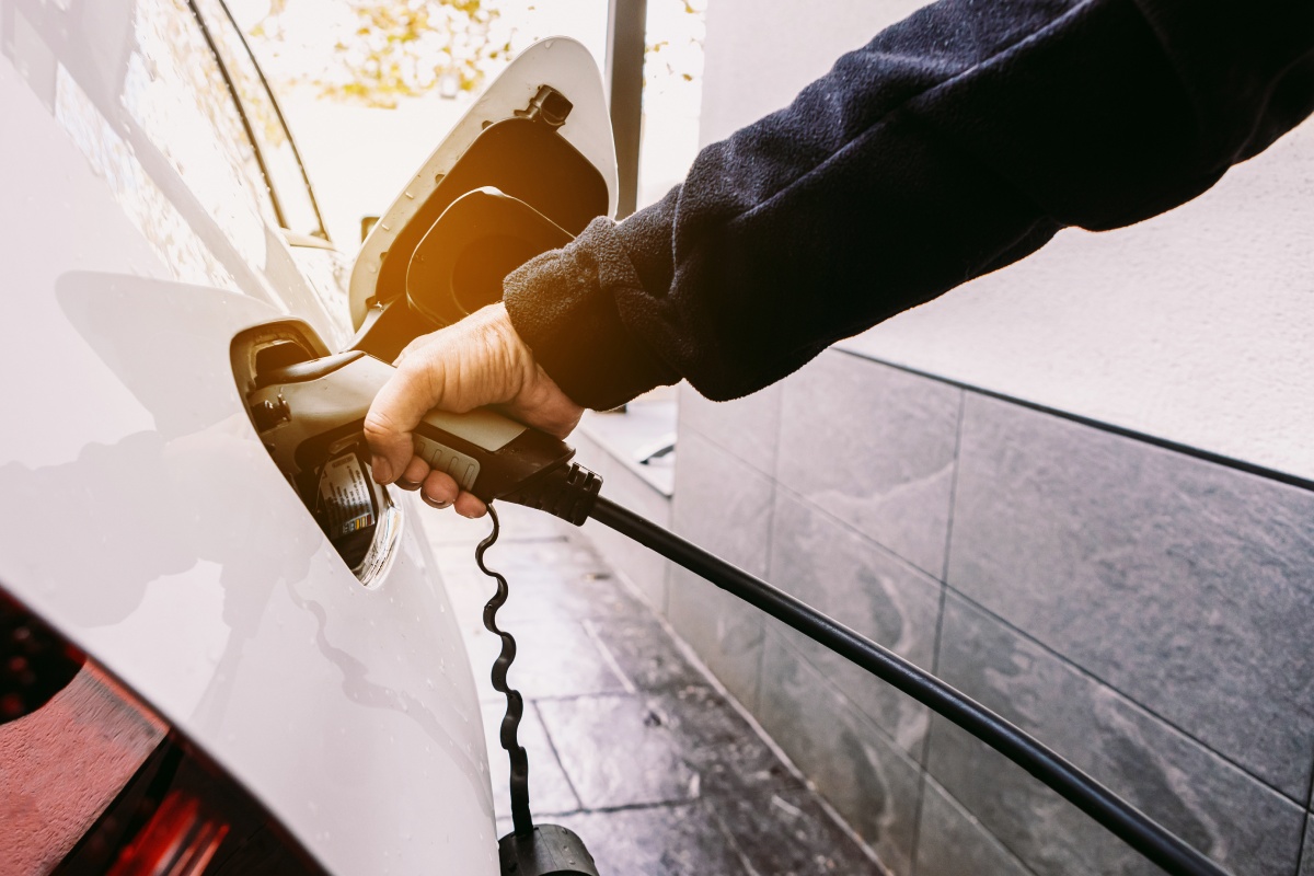 Eine Person schließt ihr E-Auto am Ladekabel an.