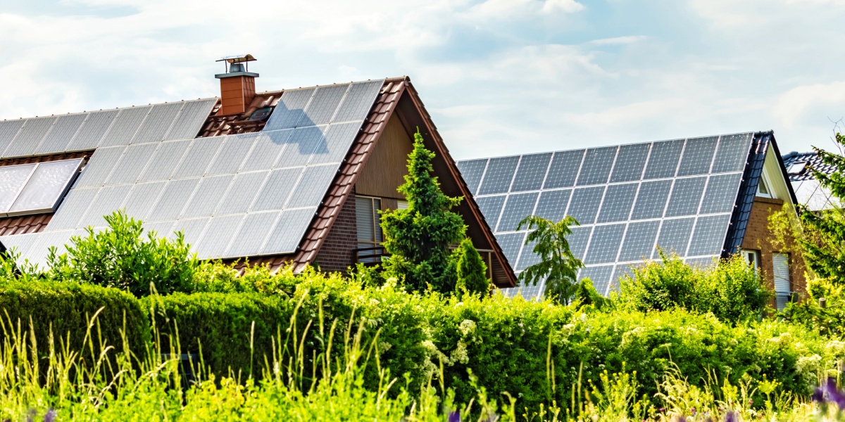 Zwei Häuser mit Solarpanelen auf den Dächern.