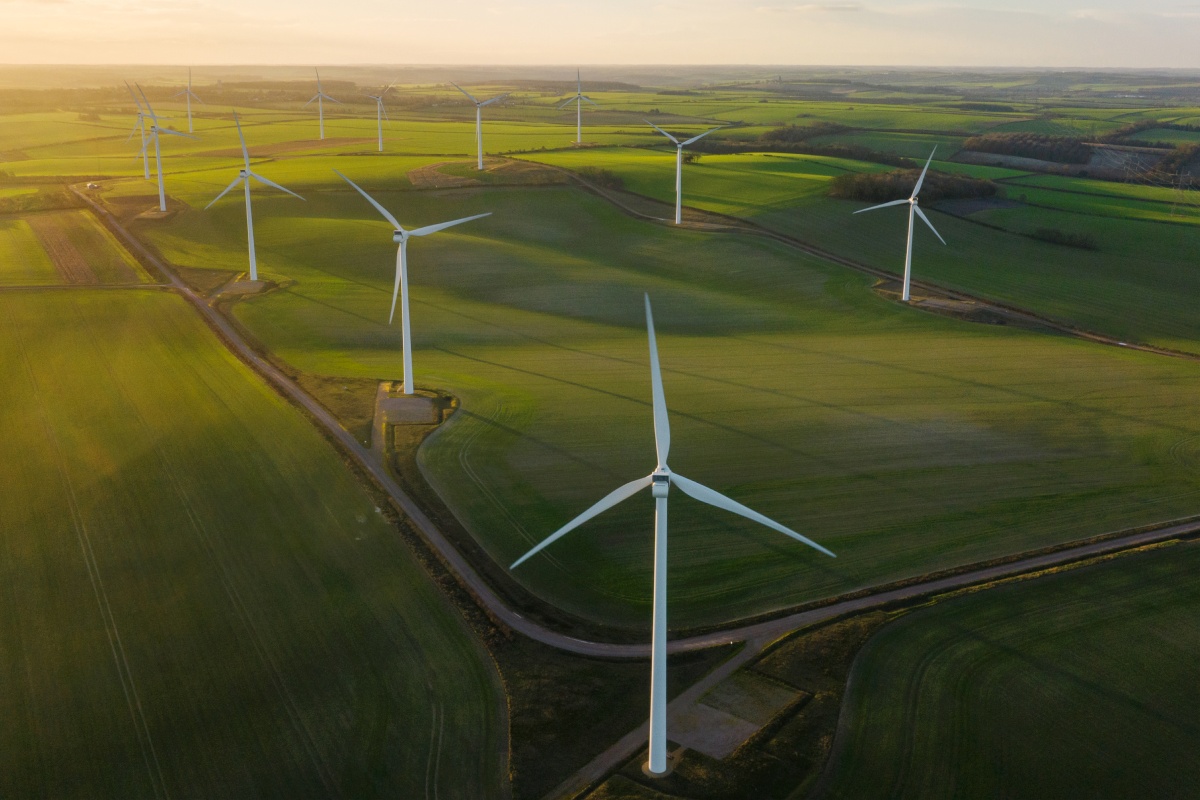 Windräder stehen auf Feldern bei Sonnenuntergang.