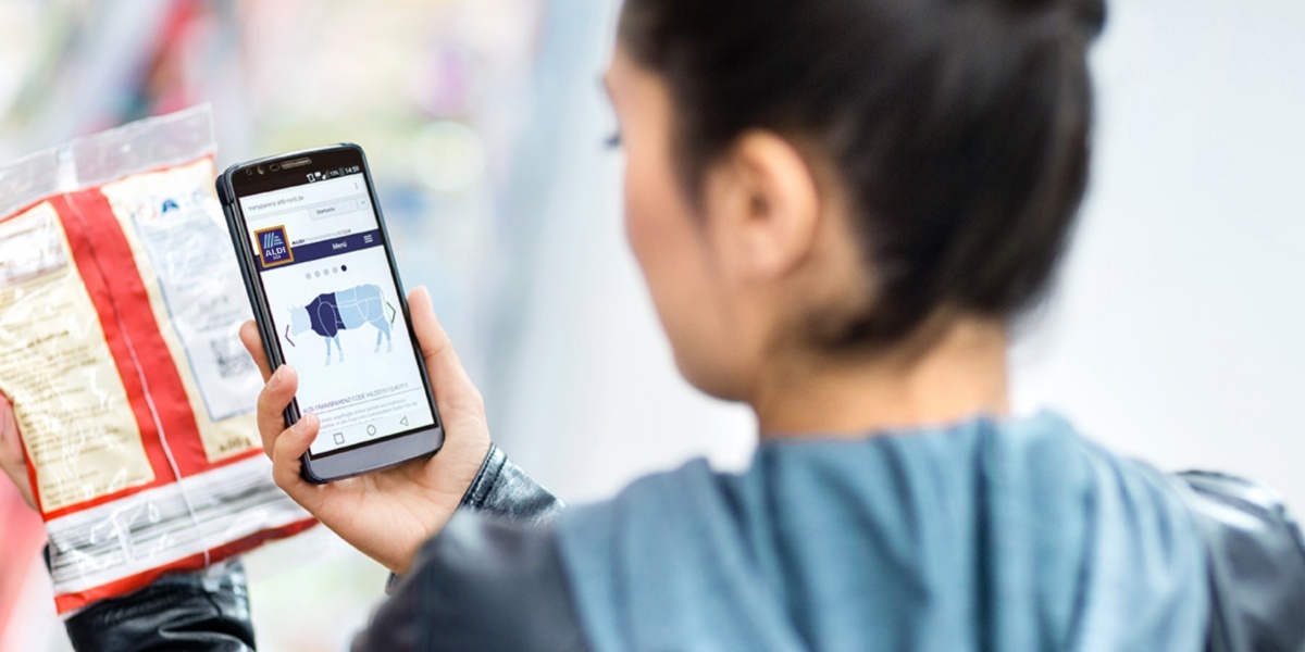 Eine Frau nutzt die Rückverfolgbarkeitsplattform bei einem Produkt in ihrer ALDI SÜD Filiale.
