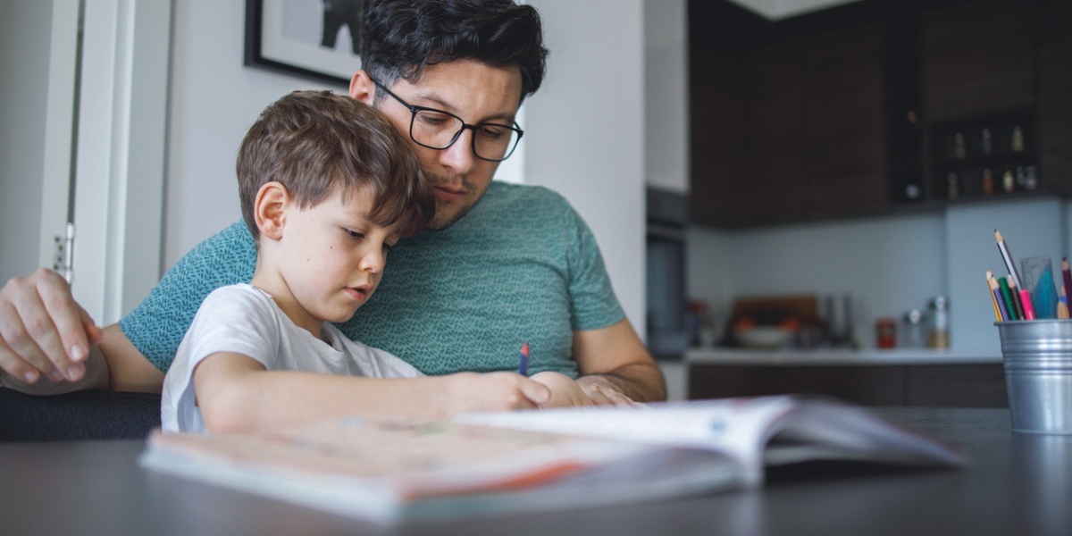 Vater hilft Sohn beim Lernen zu Hause, konzentriert und fürsorglich.