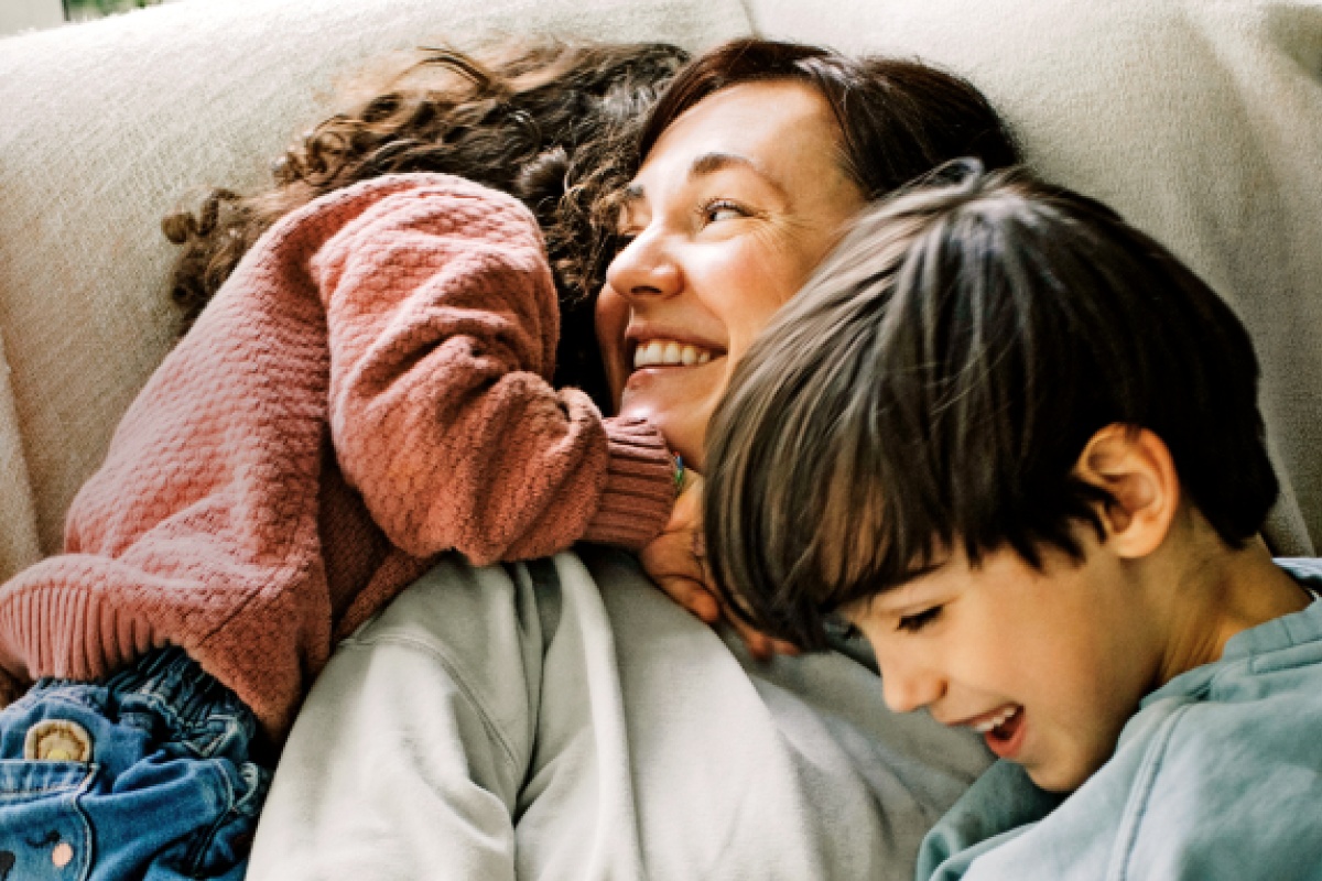 Eine Mutter albert kuschelnd mit ihren beiden Kindern herum.