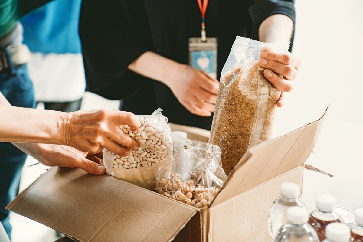 Eine Gruppe Helfer packt Lebensmittel in Kartons ein.