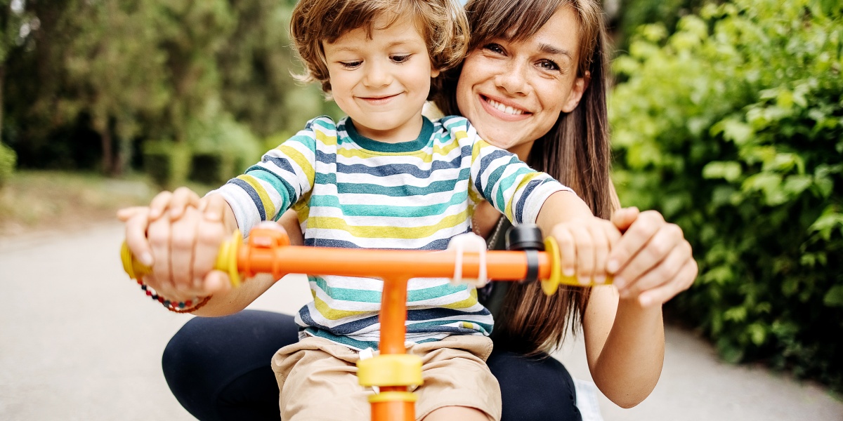 Eine Mutter hilft ihrem Kind beim Fahrrad fahren.