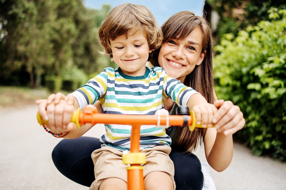 Eine Mutter hilft ihrem Kind beim Fahrrad fahren.