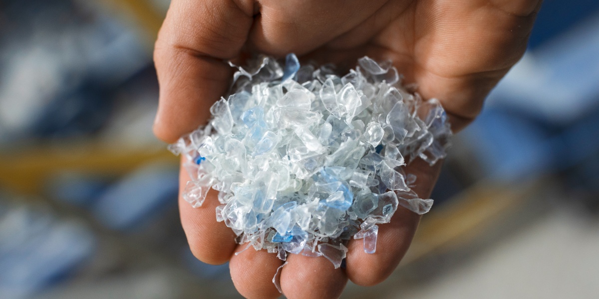 Eine Hand voll Kunststoff-Flakes für neue PET-Flaschen.