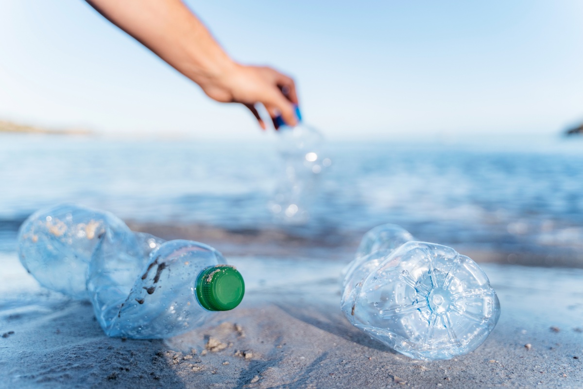 Gebrauchte Plastikflaschen liegen angespült im Sand an einem Strand.
