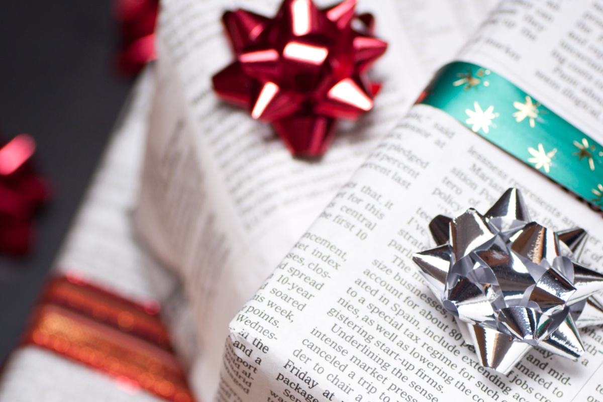 Geschenke in Zeitungspapier verpackt und mit roten und silbernen Schleifen dekoriert.
