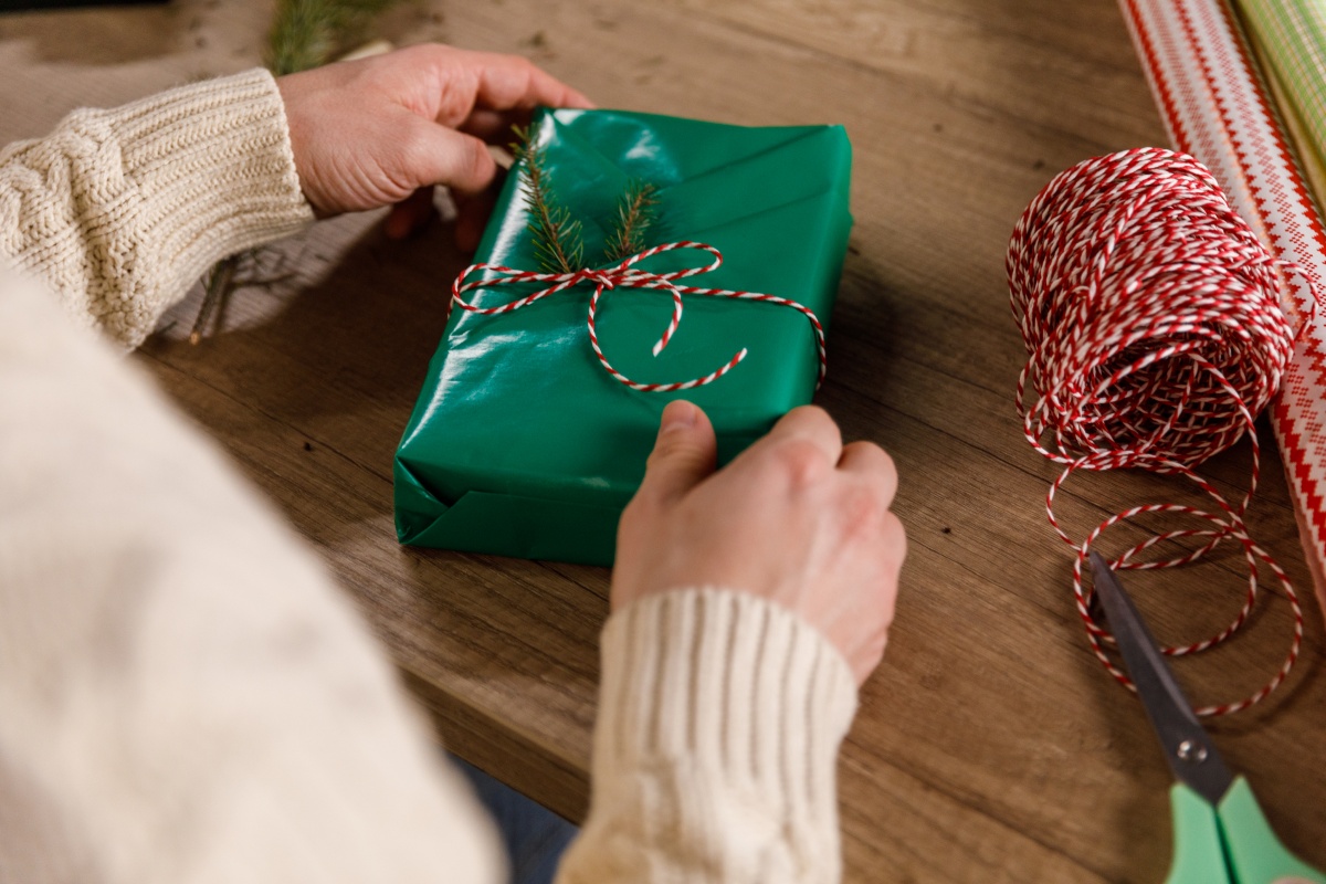 Geschenk in grünem Papier mit rot-weißer Schnur und Tannenzweig dekoriert.