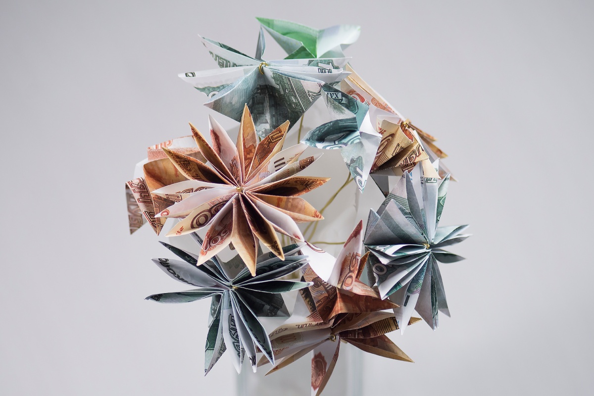 Origami-Blumen aus gefalteten Geldscheinen in verschiedenen Farben.