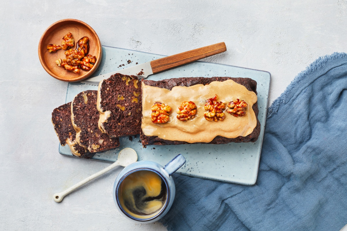 Schokoladenkuchen mit Nüssen, Erdnusscreme-Topping und kandierten Walnüssen auf einem Servierbrett.