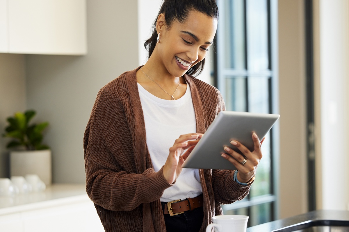 Frau bedient ein Tablet und lächelt dabei.