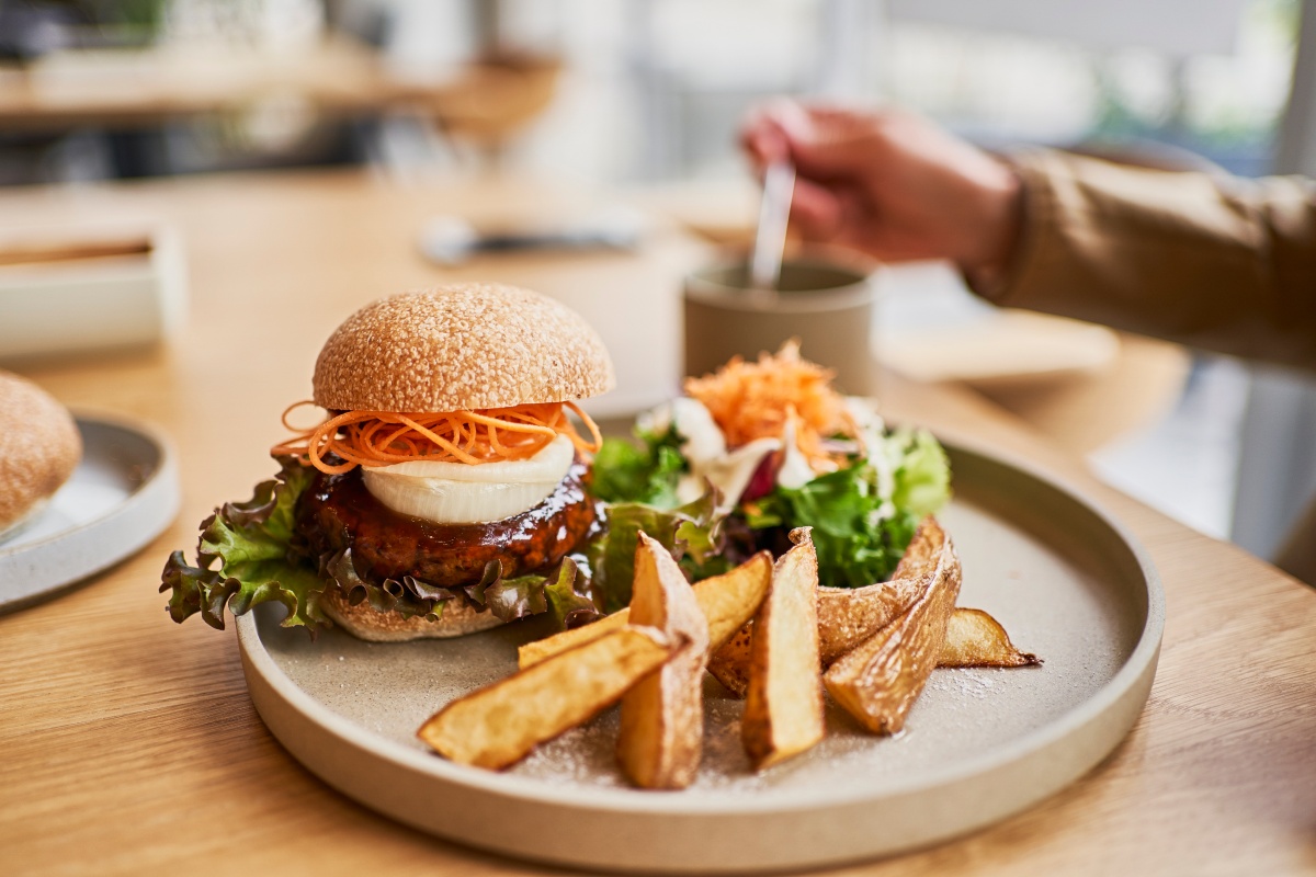 Ein angerichteter Teller mit einem veganem Burger und Kartoffelwedges.