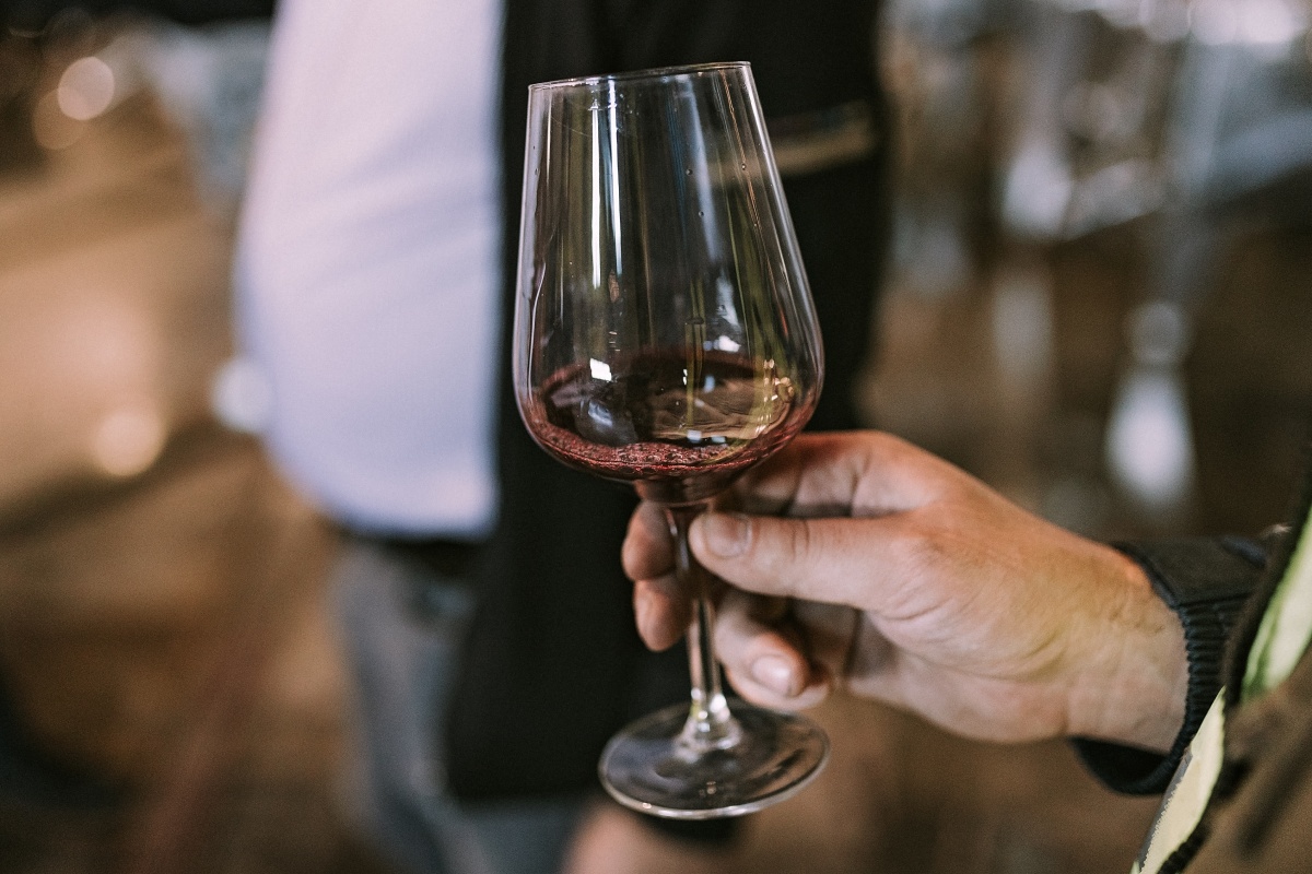 Jemand hält ein Glas mit Rotwein in der Hand.