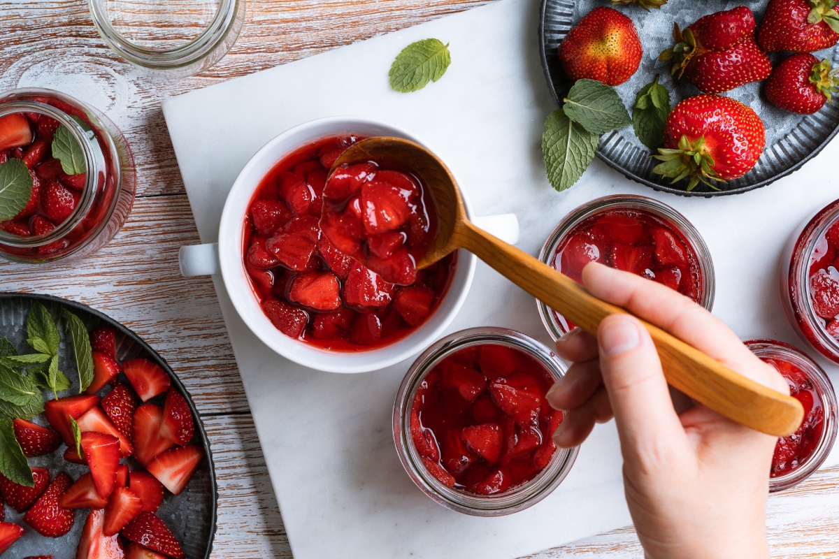 Frische Erdbeeren werden in Gläser gefüllt, um für das Einkochen im Backofen vorbereitet zu werden.