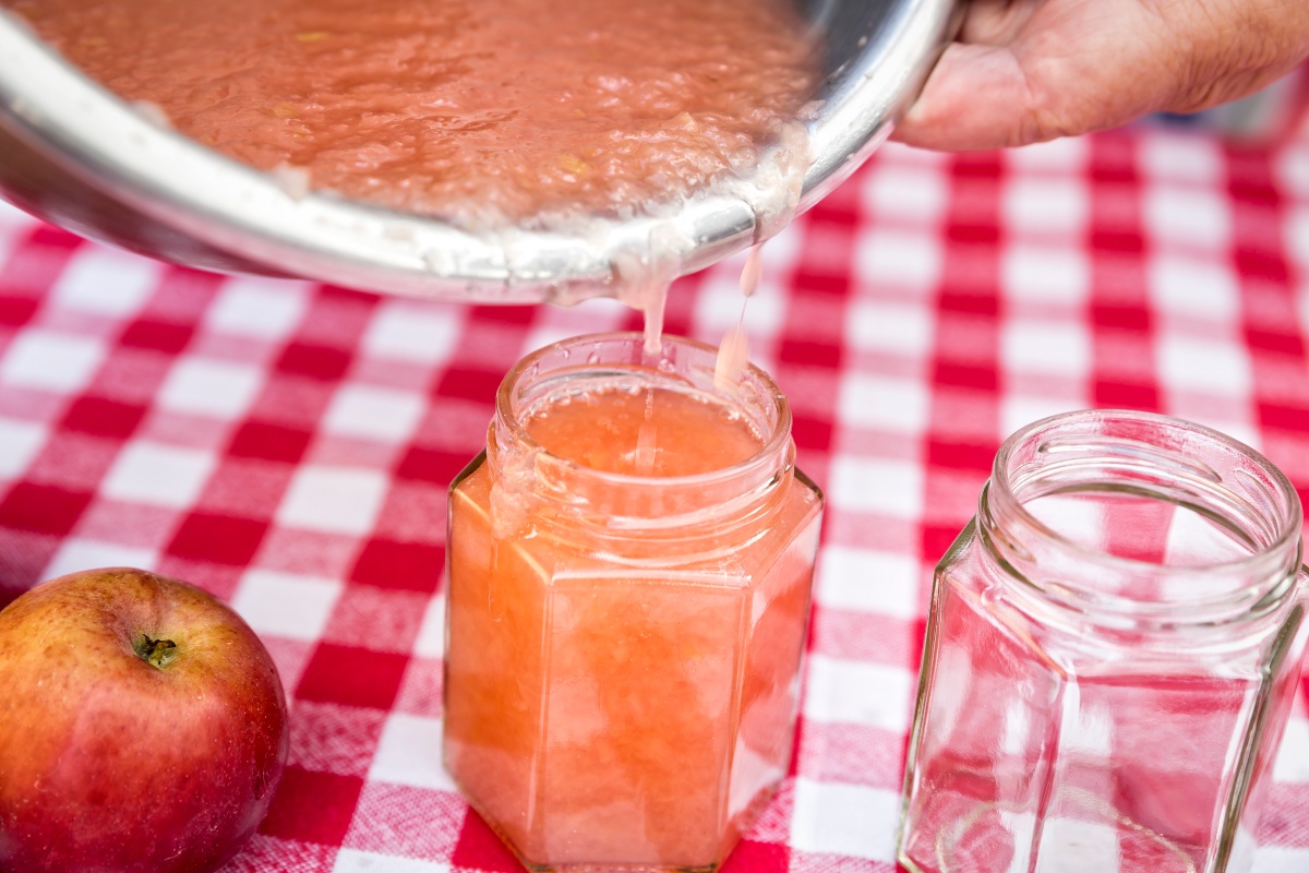 Frisch gekochtes Apfelmus wird in ein Glas gefüllt, um es anschließend im Backofen einzukochen.