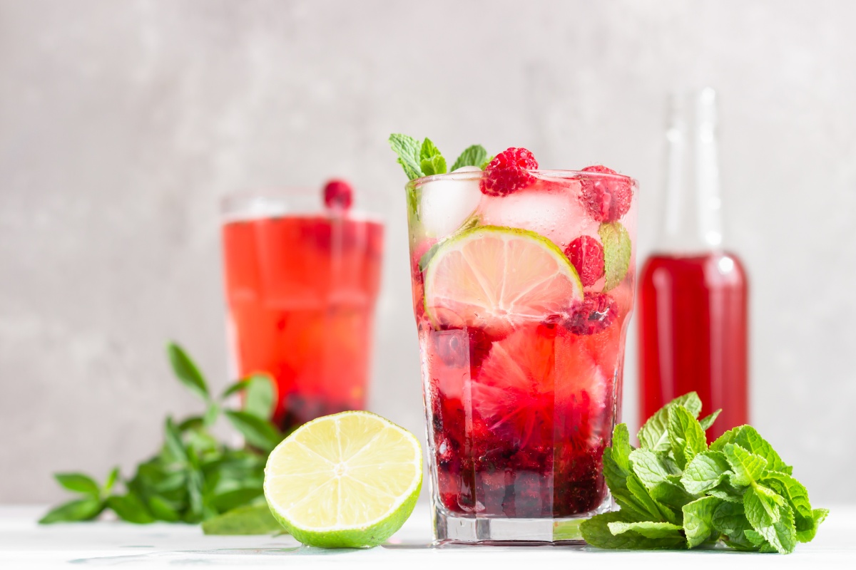 Ein Glas mit rotem Eistee, mit Limetten und Minze.