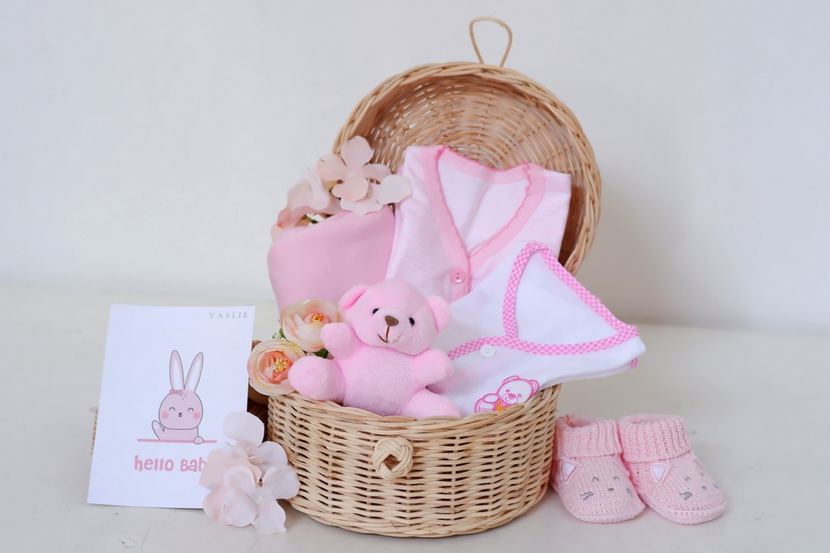Ein Geschenkkorb mit Baby-Produkten wie Strampler und Kuscheltiere.