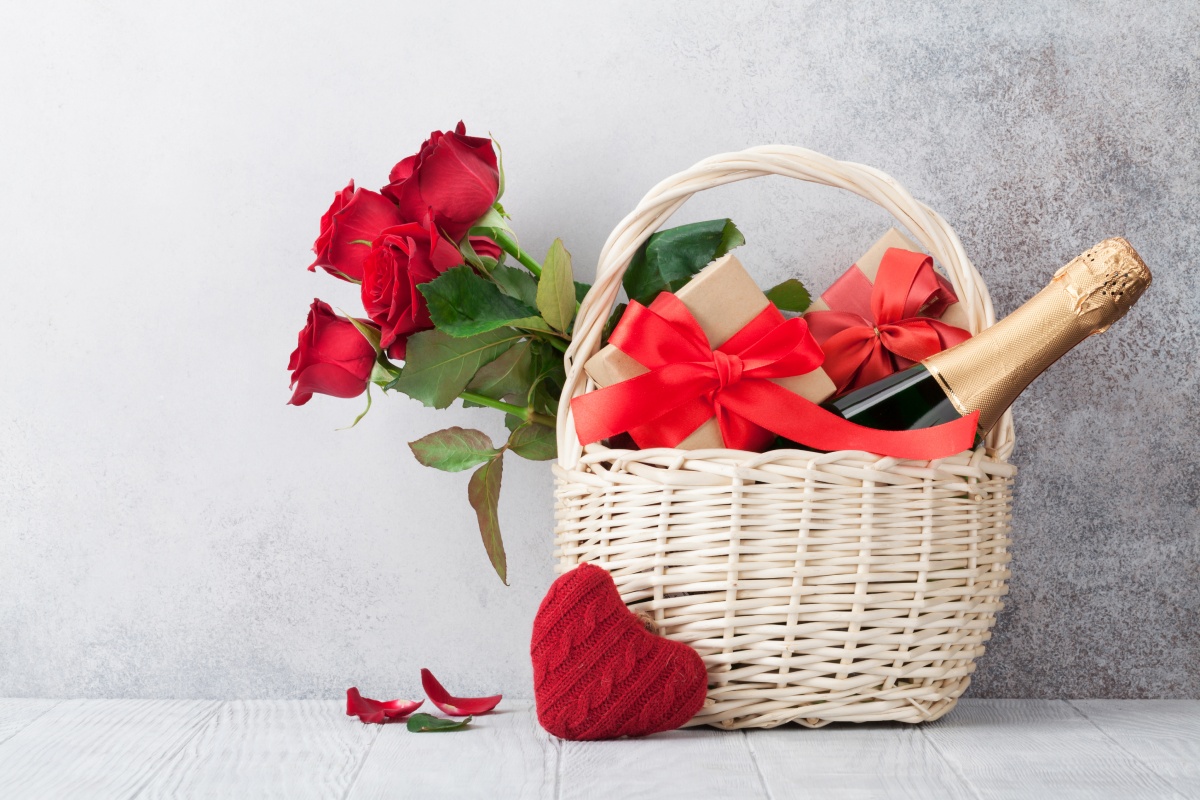 Romantischer Geschenkkorb mit roten Rosen, Wein und einem Geschenk